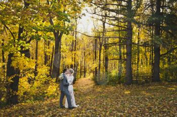 Newlyweds in beautiful modern attire in the background of bright autumn yellow forest.