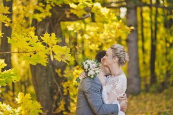 Portrait of newlyweds in sunlit autumn woods.