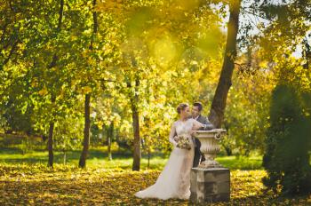 Portrait of newlyweds in autumn garden.