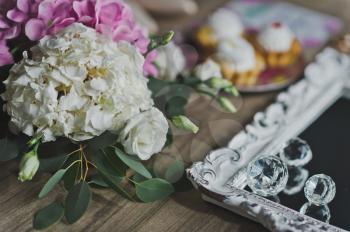 Cream cakes in the middle of the table with flowers.