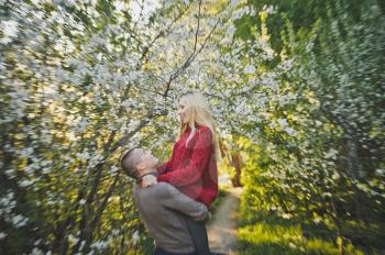 Lovers hugging on the background of flowering trees.
