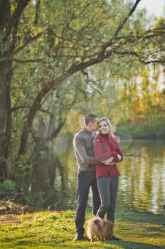 Guy and girl hugging standing on the shore of the pond.