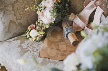 Bouquet and brides shoes on a luxurious chair.