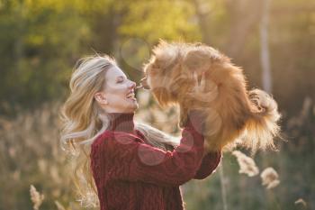 Happy mistress playing in nature with her dwarf Spitz.