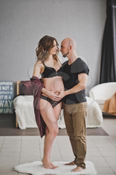 Bald husband gently stroking pregnant wife.