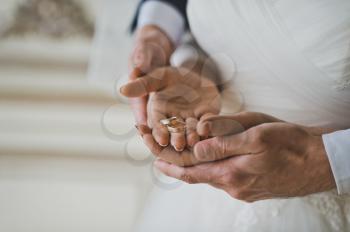 The husband supports the wifes hand with wedding rings.