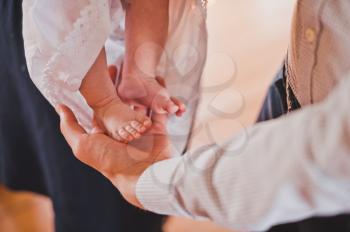 The priest rubs the baby's feet.