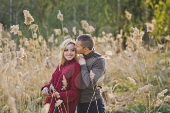 A young couple in love hugs against the background of reeds.