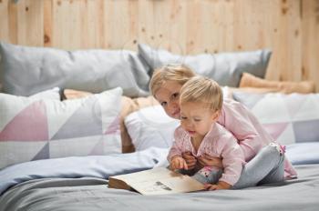 Older sister reads bedtime stories for younger sister.