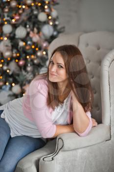 The girl with long hair sad around the Christmas tree.