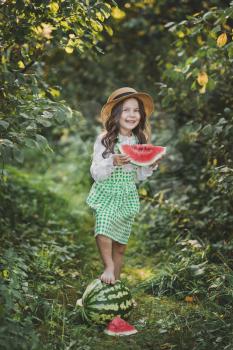 Smiling child with a piece of juicy watermelon in his hands.