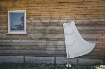 Wedding dress hanging on the Timber wall of the house.