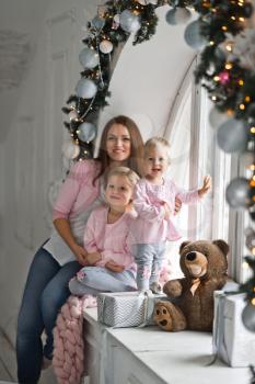A young mother with two little girls at the Christmas window.