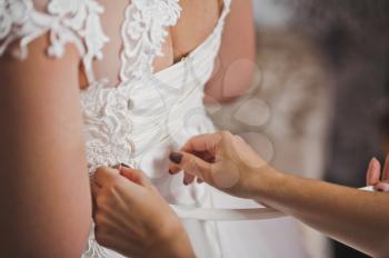 Mom helps her daughter to wear a wedding dress.