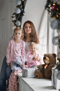 A young mother with two little girls at the Christmas window.