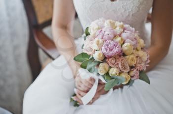 Delicate white-green wedding bouquet in the hands of the bride.