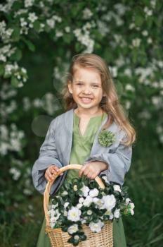 Happy young girl carries a basket of flowers.