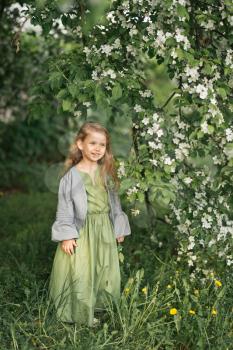 Portrait of a little girl in the spring in the flowering trees.