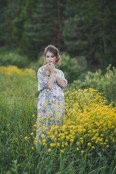 The girl on a glade of yellow flowers.