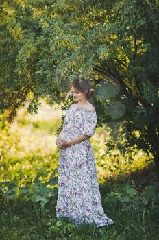 Expectant mother waiting for a miracle walks through the garden.