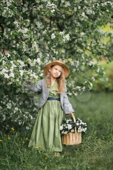 A little girl walks through the blooming garden.