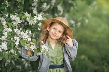 Large portrait of a child in a hat among the flowers of cherries.