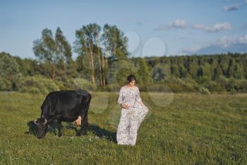 A village girl near a grazing cow.