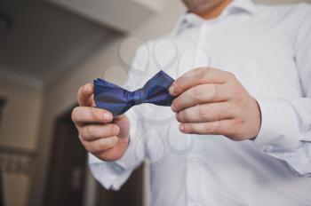 Bow tie in the hands of the groom.