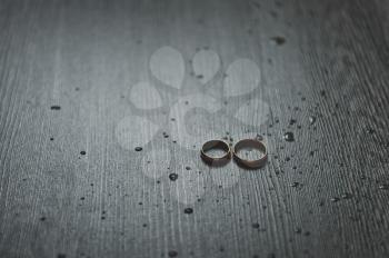 Two wedding rings on a dark table.