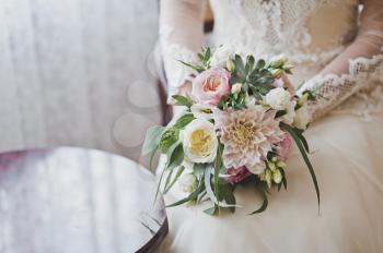 The bride in a lush white dress holding a bouquet of roses.