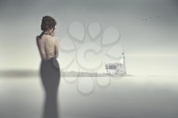 Girl in evening dress standing on the beach in heavy fog and looking at the fog and flying birds. mysticism