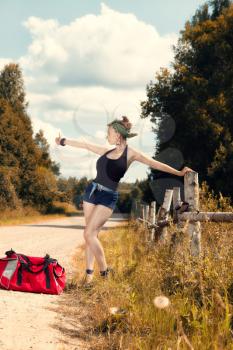 pin up girl standing on the road and catches hitchhiking