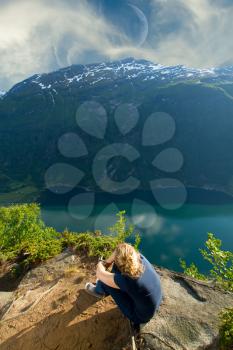 girl sitting on the edge of the fjord. ocean and mountains. Lifestyle