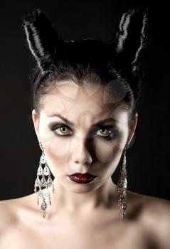 The girl in the image of the demon-tempter and hair in the form of horns. Photo taken in the studio on a background.