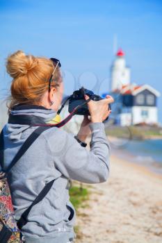 Girl shoots video at the lighthouse on the sea. In the Netherlands in the summer at the village Marken