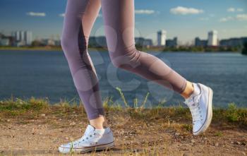 running legs of a woman against the backdrop of the city and the river