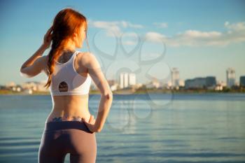 athletic woman in the background the city and the river. Sunset summer