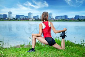 young athlete doing fitness and yoga summer evening on the river with views of the city. Lifestyle