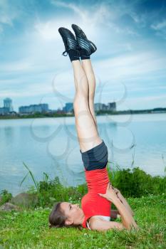 Girl athlete is pushed on one hand on a summer evening in the park by the river with views of the city. Lifestyle