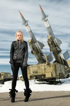 brutal girl standing on a background of military ballistic missiles