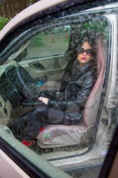 sexy girl sitting in the car and on the street the rain