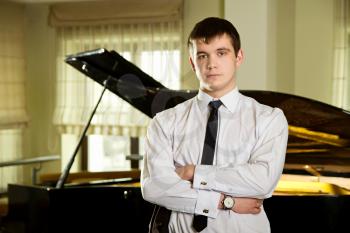 a young man standing near piano in suit