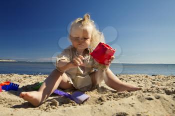 little girl playing in the sand on the beach by the sea. summer rest