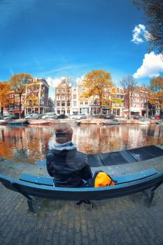 girl stands near the river and looks at the streets of Amsterdam. early autumn