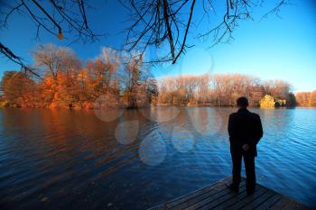  man standing on the edge of the lake and looking at the autumn landscape