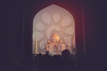 people stand in the archway and removed on the phone at the dawn of The Taj Mahal