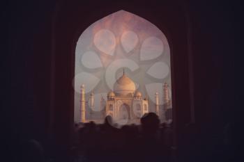 people stand in the archway and removed on the phone at the dawn of The Taj Mahal