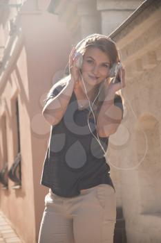 girl with headphones listening to music on the street