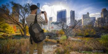 Male tourist takes pictures on a phone in Manhattan Central Park