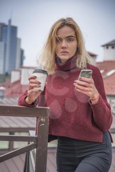 a girl drinks coffee and looks into the phone